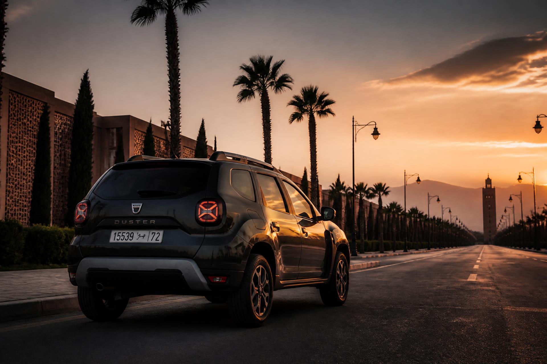 Une Dacia sombre sur un boulevard marocain au coucher du soleil